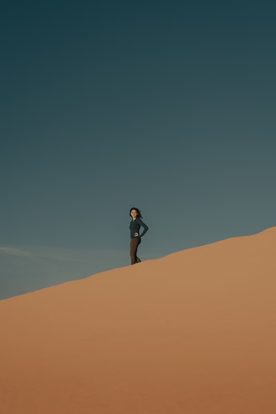 女人在黑色的衬衫和黑色的短裤站在布朗沙子白天
